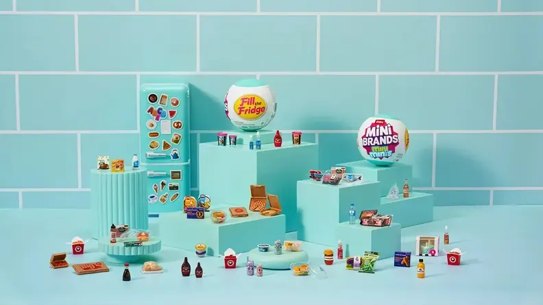 A display of the Mini Brands Fill the Fridge playset featuring a toy fridge, collectible capsules, and dozens of miniature food items.