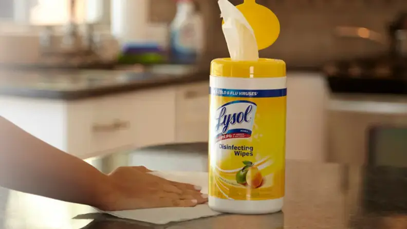 A person using a Lysol wipe on a kitchen counter.