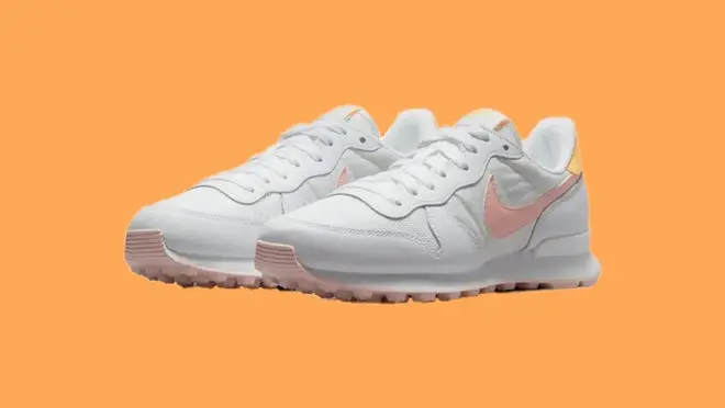 White and pink Nike Internationalist sneaker in front of orange background