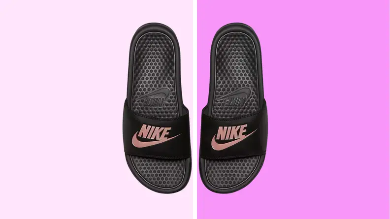 An image of a pair of black Nike slide sandals emblazoned with a pink Nike swoosh symbol.