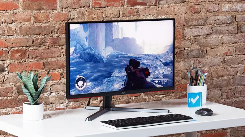 The AOC Q27G3XMN gaming monitor on a white desk, surrounded by desk supplies.