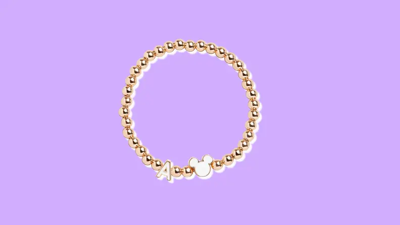 A rose gold beaded bracelet featuring an "A" initial charm and a silhouetted Mickey Mouse head.