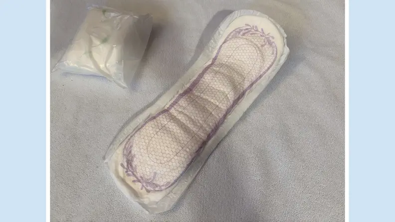 An opened Tena Ultimate Absorbency Incontinence Pad next to one folded inside of its package.