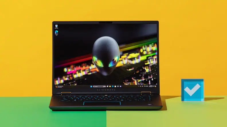 The Alienware m16 R2 gaming laptop with abstract screensaver on screen on top of a two-tone green surface.