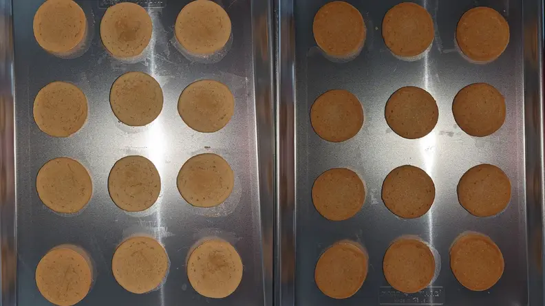 Two baking sheets with rows of different toned sugar cookies.