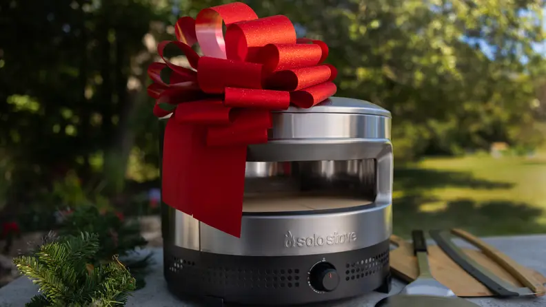 Close-up of a Solo Stove pizza oven decorated with a large red bow, making it a standout Christmas gift idea for anyone who loves backyard pizza nights.