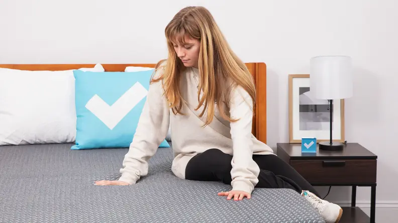 A person sitting on the Tuft & Needle Mint hybrid mattress.
