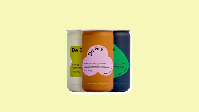 Three De Soi cans on a yellow background