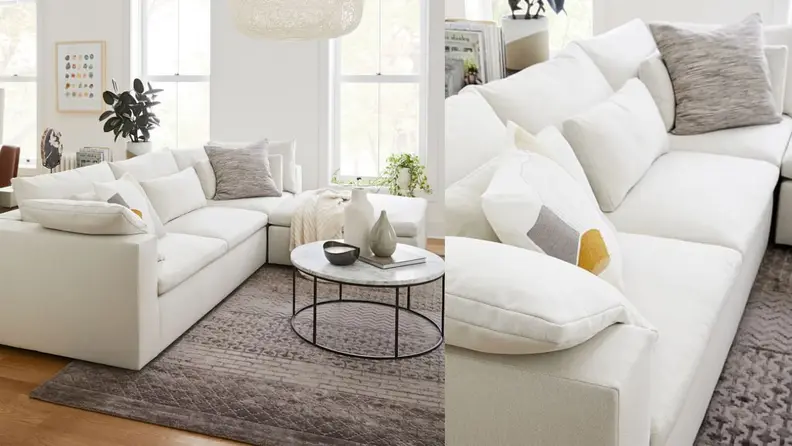 A puffy white couch on a grey rug and in front of a round coffee table.