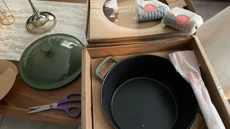 Our Place’s Cast Iron Perfect Pot in sage green color inside of cardboard box after being opened.