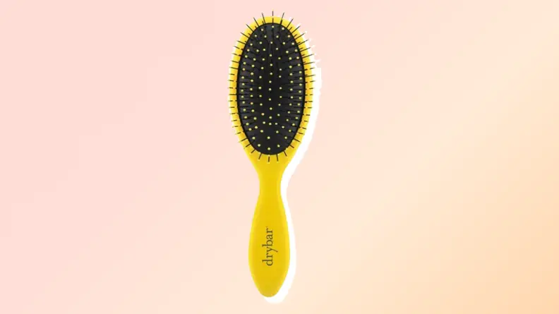 One of the best hair brushes from Drybar against a red and orange background.
