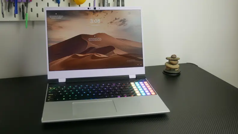The Framework Laptop 16 on a black desk next to a stack of rocks.