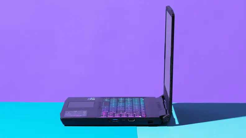 An open laptop viewed from a 90-degree angle against a blue and purple backdrop.