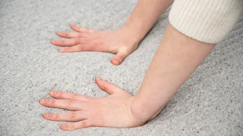 a woman's hands press into the surface of the Casper mattress