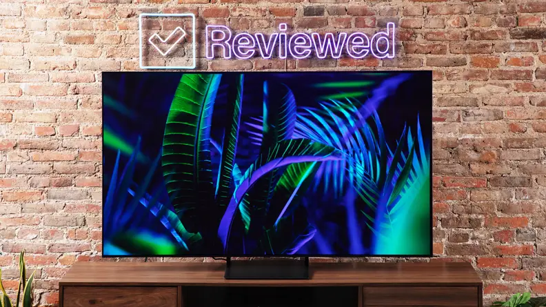 The Samsung S90C QD-OLED TV on an entertainment center on a brick background.