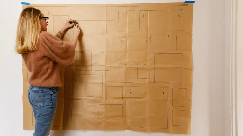 A woman hammers a nail into a wall