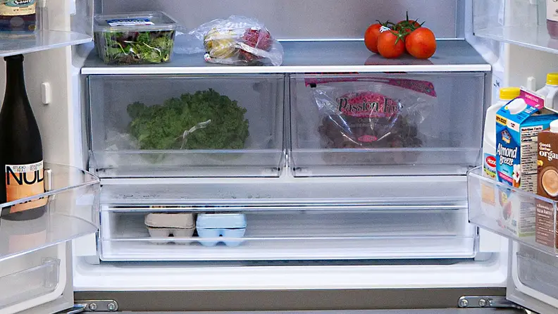 A close-up of the fridge's crisper drawers, stocked with fresh produce.