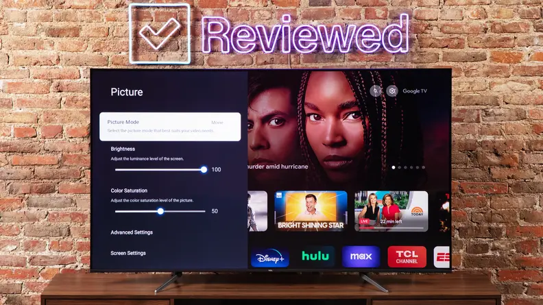 The TCL Q6 displaying a settings menu while positioned in front of a brick wall
