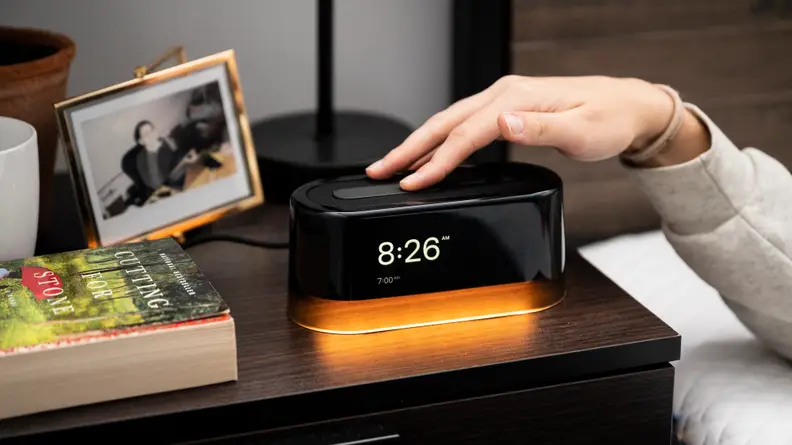 A person reaches over to press a button atop the Loftie alarm