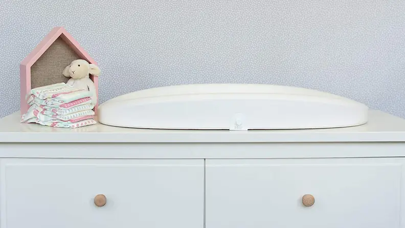 White changing table on top of dresser.