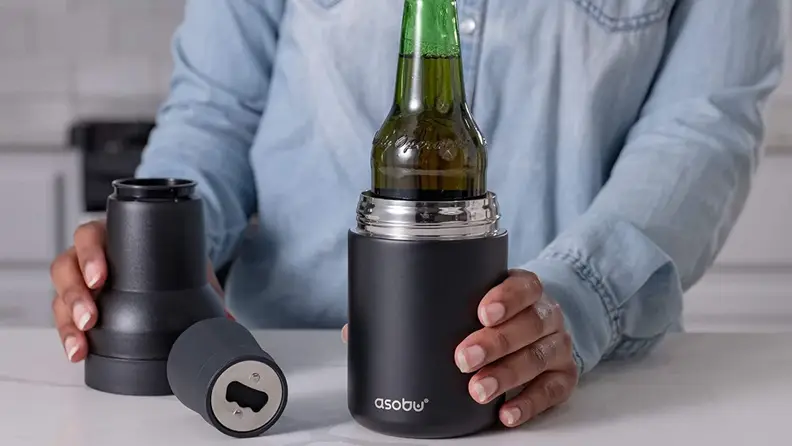 A person hold a beer bottle in an insulated double-walled can cooler.