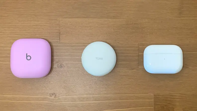The cases for the Beats Fit Pro, LG T90Q, and Apple AirPods Pro sit side by side on a wooden table.