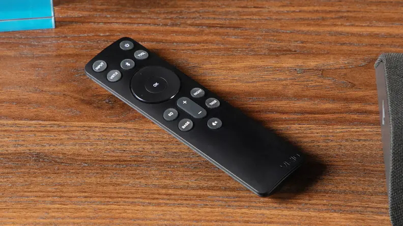 A remote for the Vizio M-Series All-in-One M213AD-K8 Dolby Atmos Soundbar on a wooden tabletop surface.
