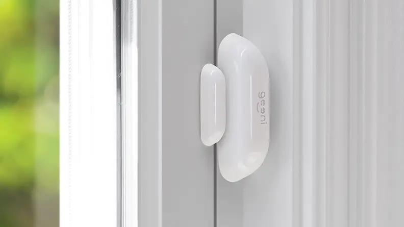 White oval smart sensor mounted on white door.