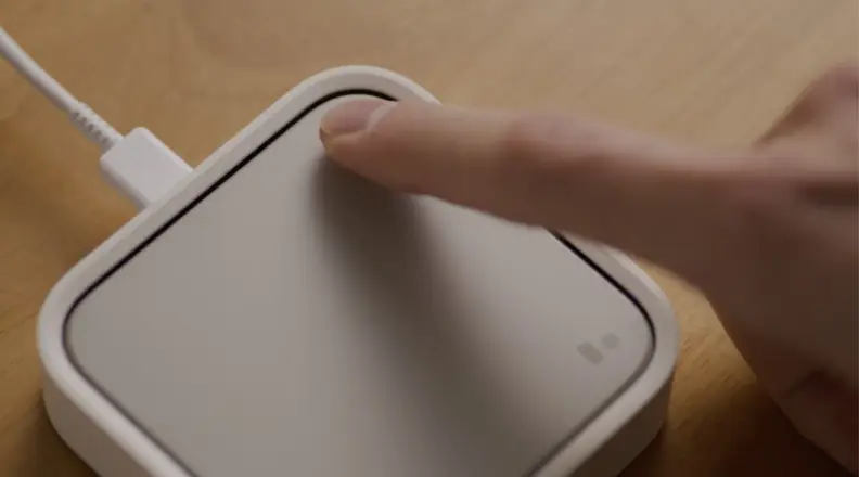 A finger pressing down on a smart home hub.