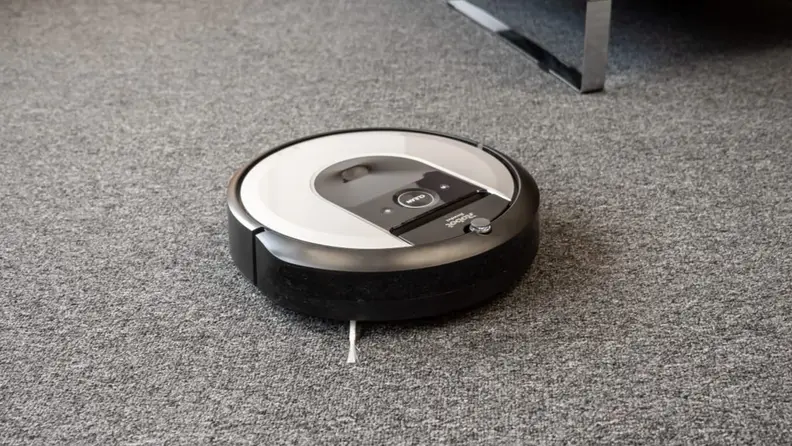 Silver and gray robot vacuum on carpeted floor.