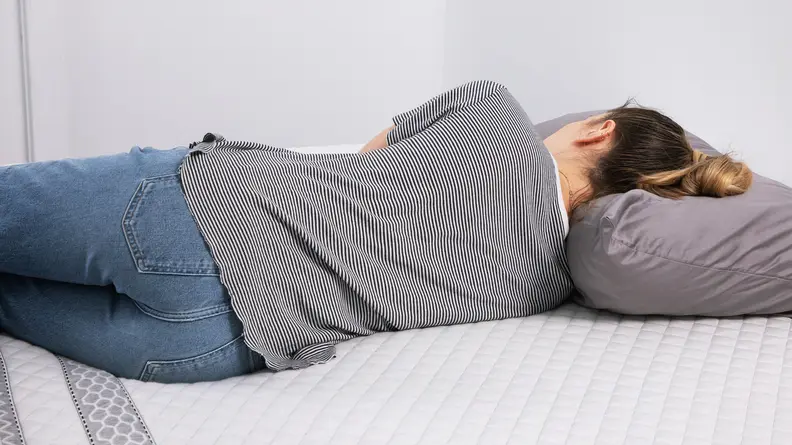 A person lying on their side on the Leesa Sapira hybrid mattress