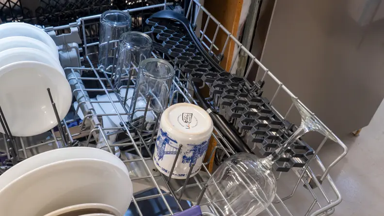 The Beko DDT39434X's upper rack is shown filled with dishes, including a wine glass in a honeycomb holster.