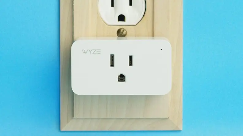 White, rectangular wall plug plugged into outlet on blue wall.