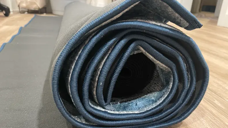 A Ruggable Premium Rug rolled up on a hardwood floor.