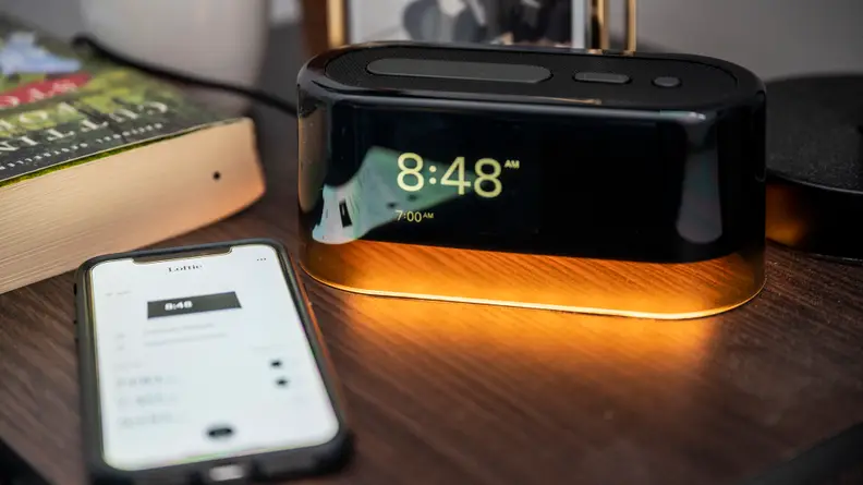 a phone with the loftie app on a bedside table next to the Loftie clock