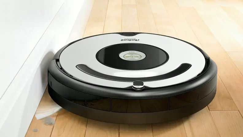 A robot vacuum cleans a wood floor.