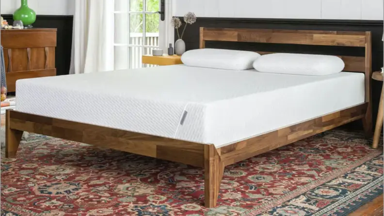the Tuft & Needle original mattress on a brown wood bedframe with a pink carpet