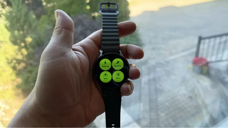 A hand holding up the smartwatch displaying a green menu.