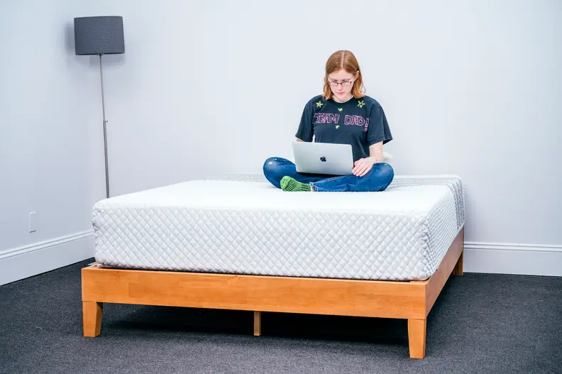 a person sits atop the Leesa hybrid working on their computer