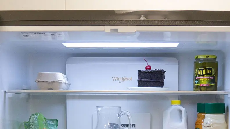 A close-up of the Whirlpool WRQA59CNKZ's crisper drawers. The fridge is fully stocked with food, and the crispers hold various fruits and vegetables.