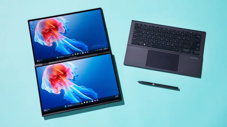 Dual screens of the 2024 Asus Zenbook Duo laptop sitting next to keyboard and stylus pen.