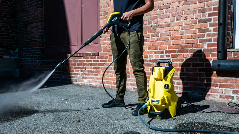 The Karcher K4 Power Control pressure washer is shown cleaning asphalt.