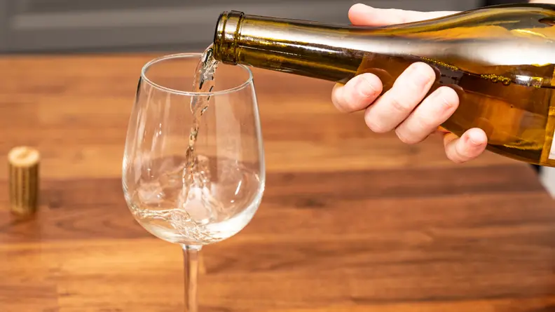 Pouring a glass of white wine into a white wine glass
