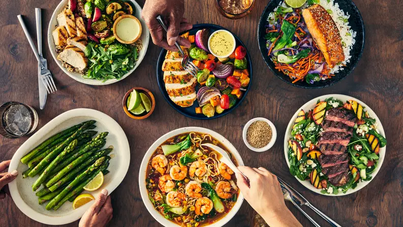 A colorful spread of HelloFresh meals featuring steak, salmon, shrimp ramen, and veggies, promoting the latest HelloFresh promo code offer.