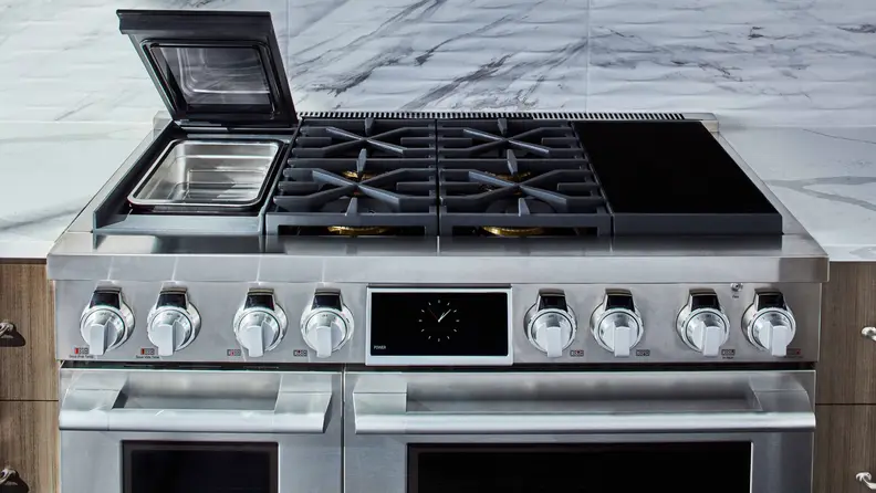 The cooktop of a luxury oven range, with an open lid to a sous vide compartment on left and induction cooktop surface on right.