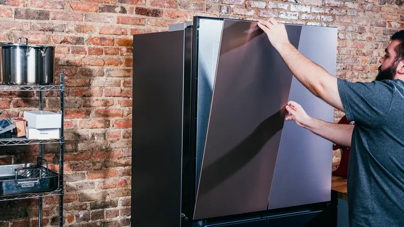 A person installs the front panel of a refrigerator