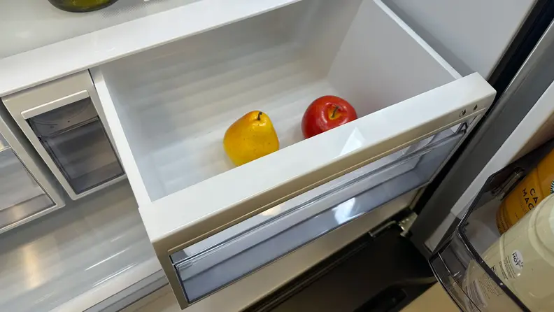 A close-up of a crisper drawer pulled out at a slight angle, showcasing how the side of the drawer can bump into its housing and create friction. It also shows how the drawer can hit the main door if it's not open the whole way.