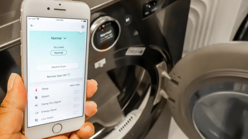 A hand holds up the LG app in front of an LG The LG DLEX6700B