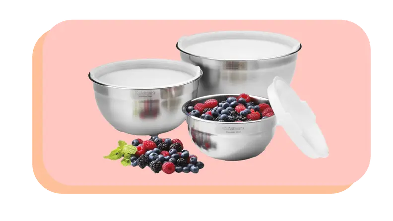 Set of three stainless steel mixing bowls with lids and one bowl has mixed berries inside.