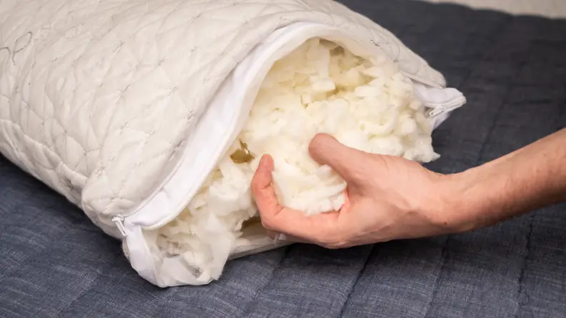 a hand holding shredded stuffing from the Coop Home Goods Original Pillow